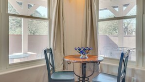 A room with a round table and two chairs, a decorative bowl on the table, and a window with curtains.