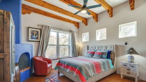 A bedroom with a bed, a red chair, a nightstand, and a window with curtains.
