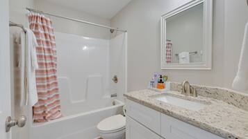A bathroom with a bathtub, toilet, sink, and a mirror.