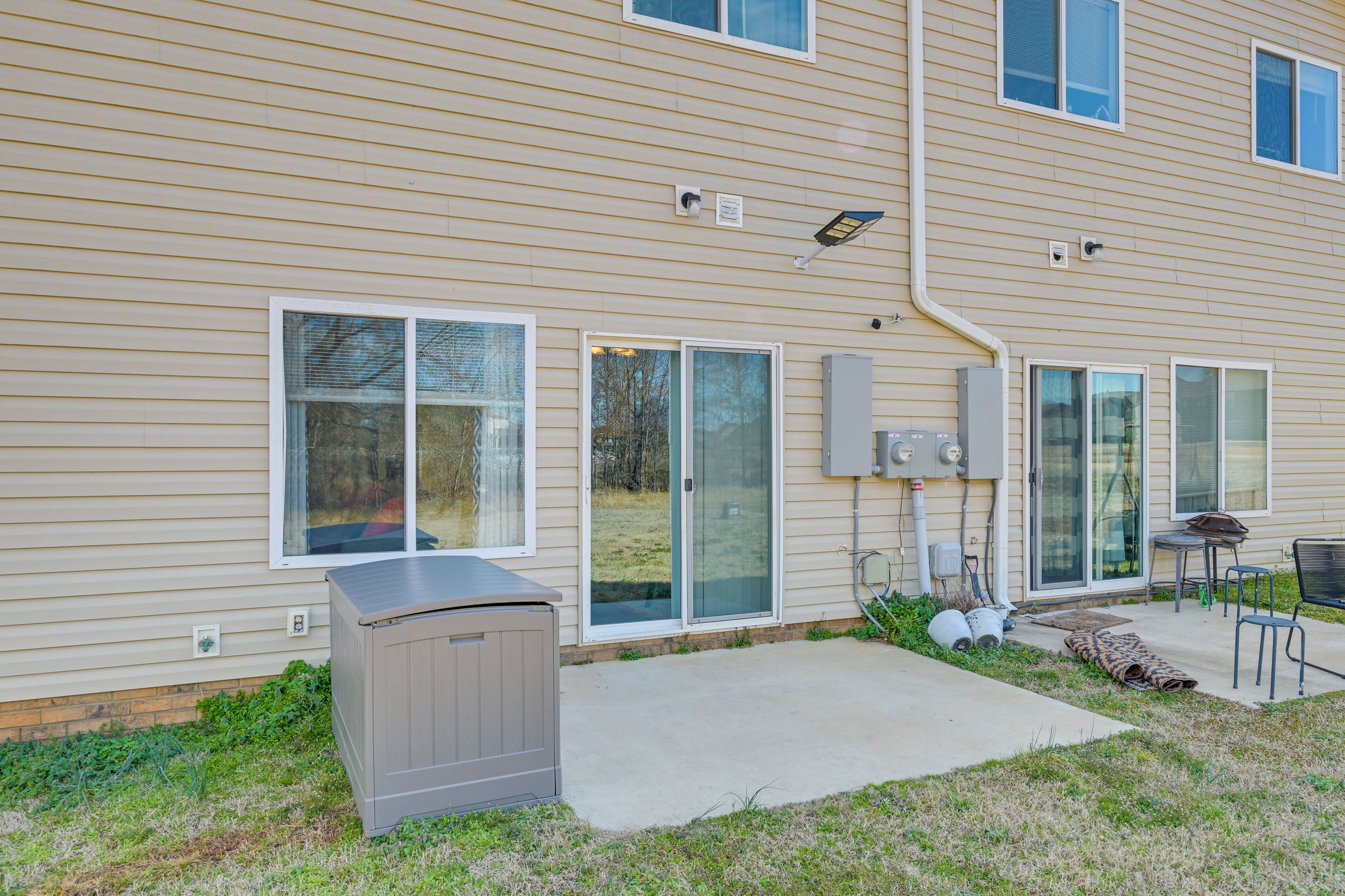 A two-story building with a patio area featuring a grill, outdoor seating, and a covered play area.