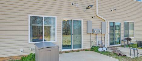 A two-story building with a patio area featuring a grill, outdoor seating, and a covered play area.