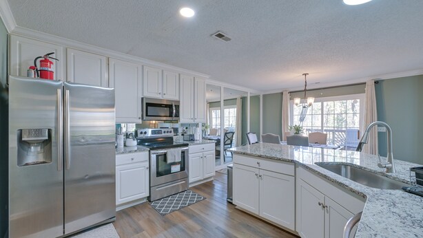 A modern kitchen with stainless steel appliances, white cabinetry, and a large island with a sink. - Home 9 Mi to Uptown Charlotte: Dogs Welcome! (Charlotte)