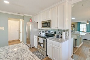 A modern kitchen with white cabinets, stainless steel appliances, and a granite countertop.