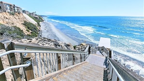 Un hotel frente al mar con una escalera de madera que baja a la playa.