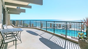 Un balcón con piscina, mobiliario exterior y vista despejada al océano.