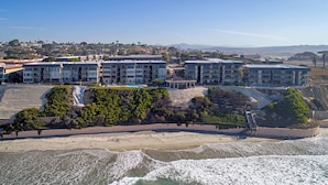 Un hôtel situé sur la côte, composé de plusieurs bâtiments, avec une plage et une vue sur l’océan.