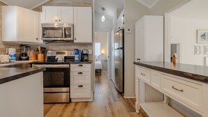 Una cucina moderna con mobili bianchi, elettrodomestici in acciaio inossidabile e pavimento in legno.