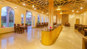Un vaste espace intérieur doté d’un bar central en bois, de plusieurs coins salon et de grandes fenêtres offrant une vue sur l’extérieur.