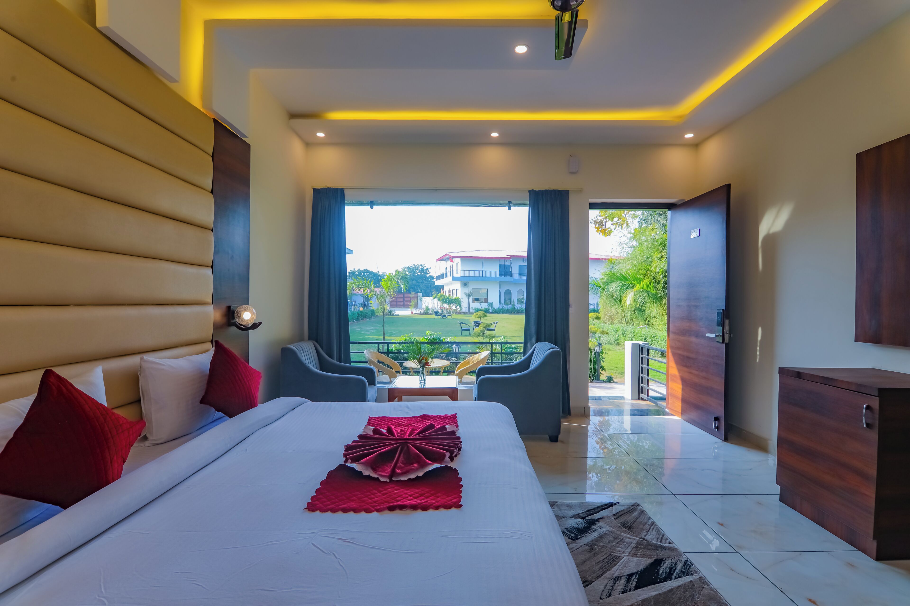 A modern hotel room with a large bed, a view of the outdoors, a balcony, and a dining area.