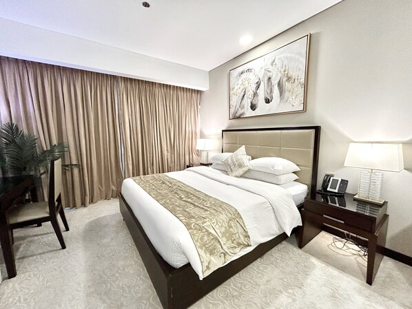 Habitación de hotel con una cama grande, una mesita de noche con lámpara, teléfono y espejo.