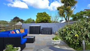 Eine Terrasse mit einer blauen Couch, einer schwarzen Bank und einer Steinmauer.