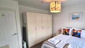 Ein Schlafzimmer mit einem Bett, einem weißen Kleiderschrank und einem Bild an der Wand.