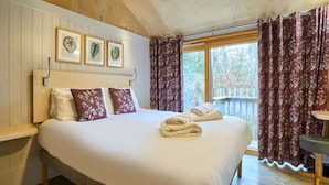 A bedroom with a large bed, a wooden headboard, framed leaf artwork, and a window with curtains. - Host Stay Strength (Wareham)