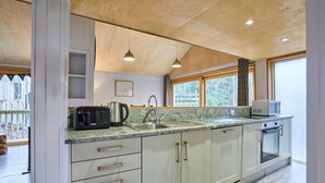 Una cocina moderna con armarios blancos, encimera de granito, cafetera, hervidor, microondas y un lavabo.