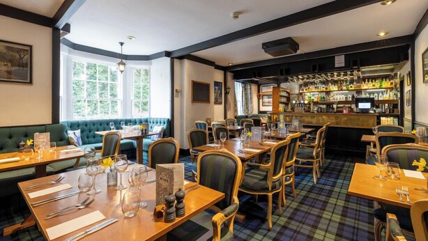 A restaurant with tables set for dining, a bar area, and a green seating area. - Bein Inn hotel  (Perth)