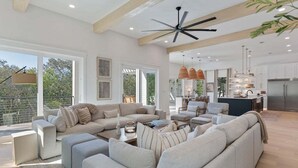 A spacious living area with a large sofa, coffee table, and a dining area with pendant lights. - Sleeps 20! Rooftop GULF VIEWS, Private Pool, LSV/golf cart, Bikes, 2 Kitchens! Pet Friendly! (Santa Rosa Beach)