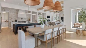 A modern kitchen with a central island, pendant lighting, and a dining area with a large table and chairs. - Sleeps 20! Rooftop GULF VIEWS, Private Pool, LSV/golf cart, Bikes, 2 Kitchens! Pet Friendly! (Santa Rosa Beach)