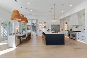 A modern kitchen with a central island, pendant lighting, and a stone backsplash. - Sleeps 20! Rooftop GULF VIEWS, Private Pool, LSV/golf cart, Bikes, 2 Kitchens! Pet Friendly! (Santa Rosa Beach)