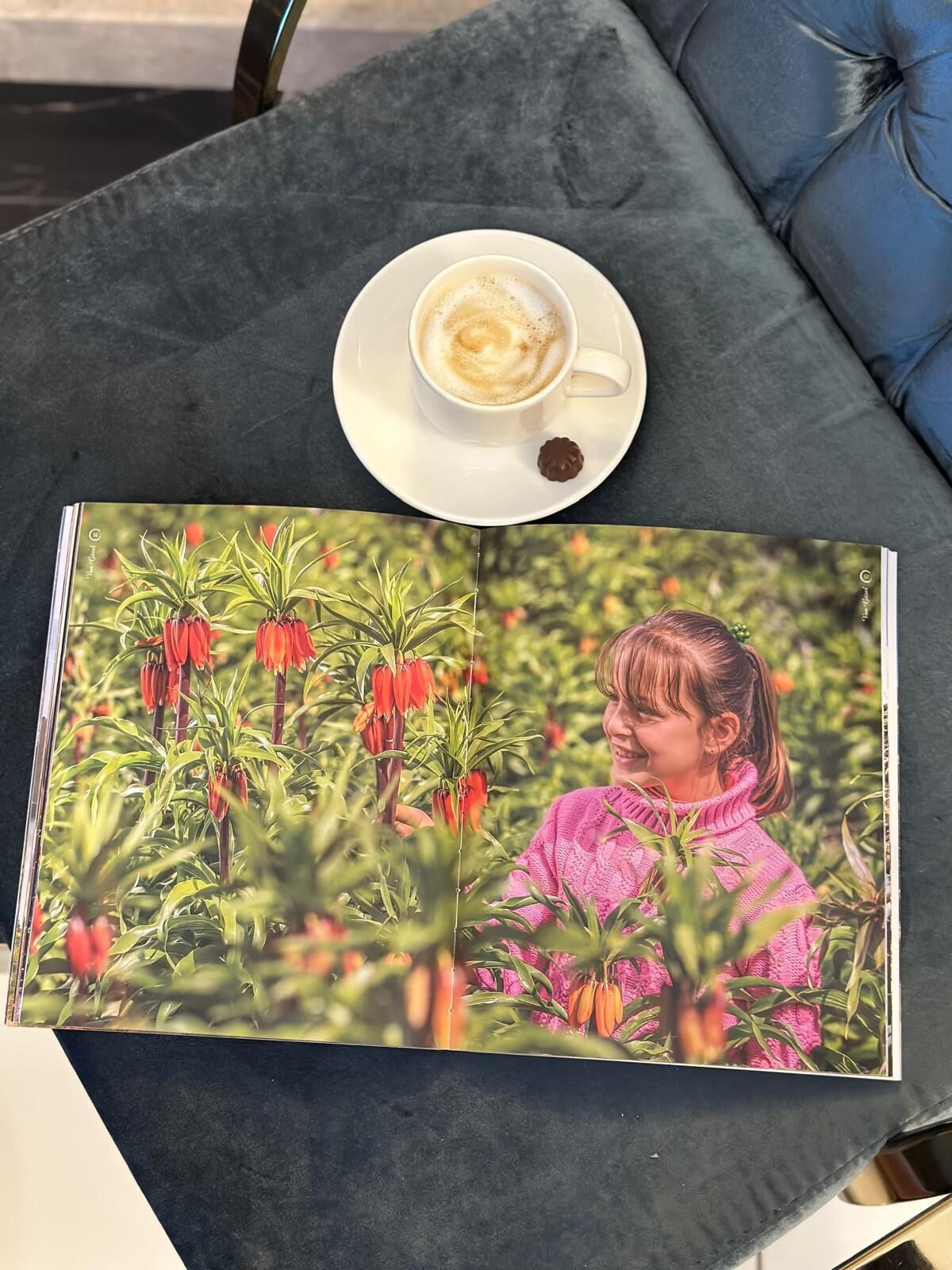 Una mesa con un libro, una taza de café y un bombón de chocolate.