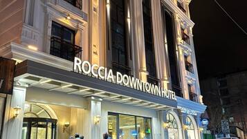 Hotel Roccia Downtown con fachada clásica, amplias ventanas y una entrada destacada.