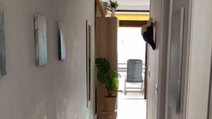 Un couloir doté d’un plancher en bois, d’un luminaire au plafond et d’une porte sur le côté droit.
