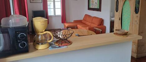 A kitchen with a microwave, coffee maker, and a wooden table with a bowl.