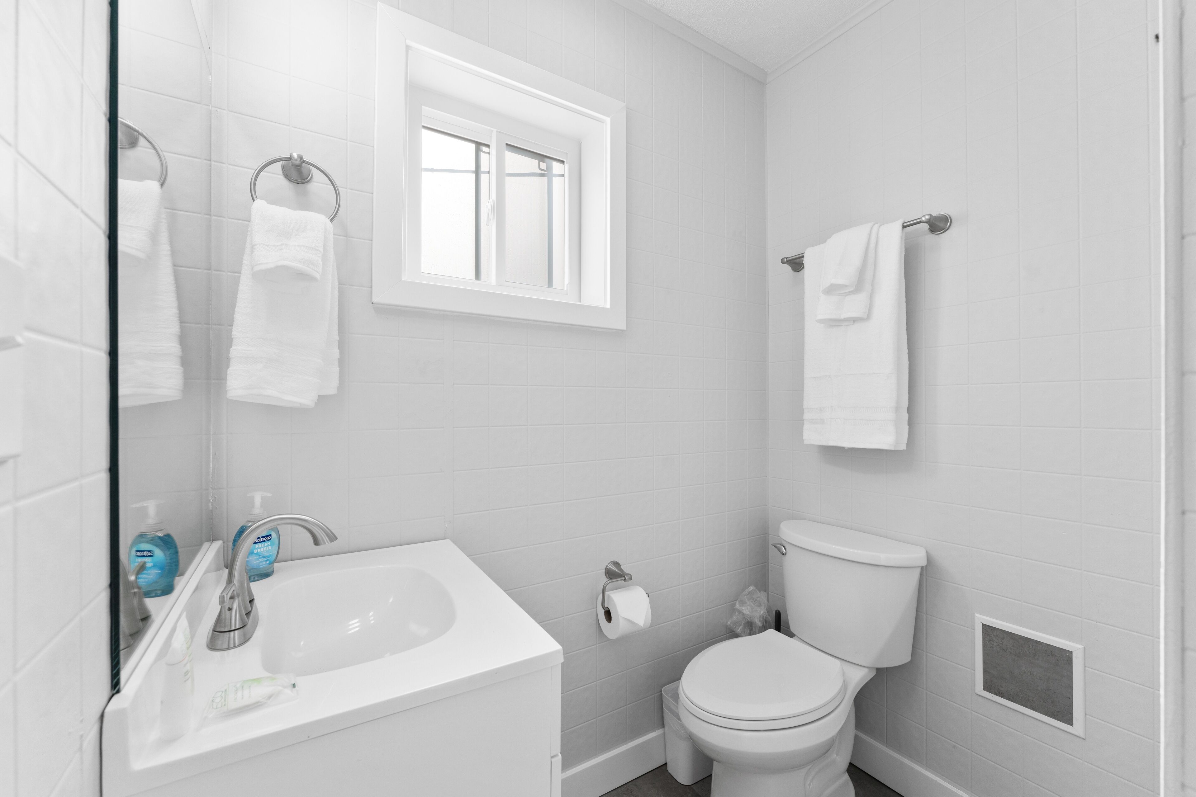 A modern bathroom with a white sink, toilet, and towel rack.