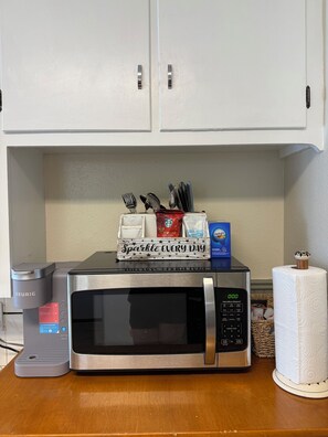 Una cucina con forno a microonde, macchina da caffè e un cartello che recita 'Sparkle Every Day'.