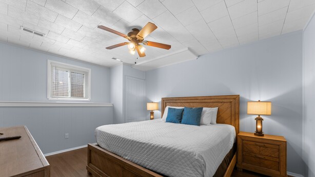 A bedroom with a wooden bed, two bedside tables with lamps, a ceiling fan, a window with blinds, and a desk. - Sc2- Silver Cove 2 2 Bedroom Condo (Branson)