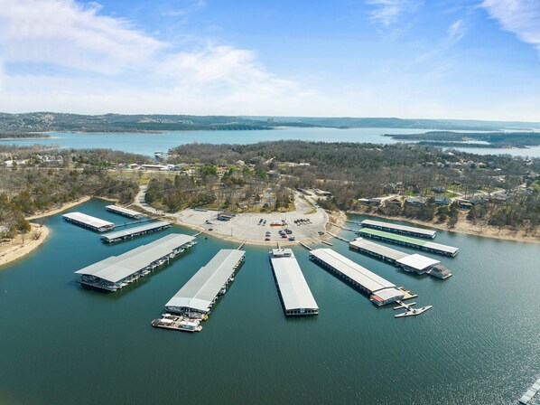 Vista aérea de un puerto deportivo con varias embarcaciones amarradas y un estacionamiento central.