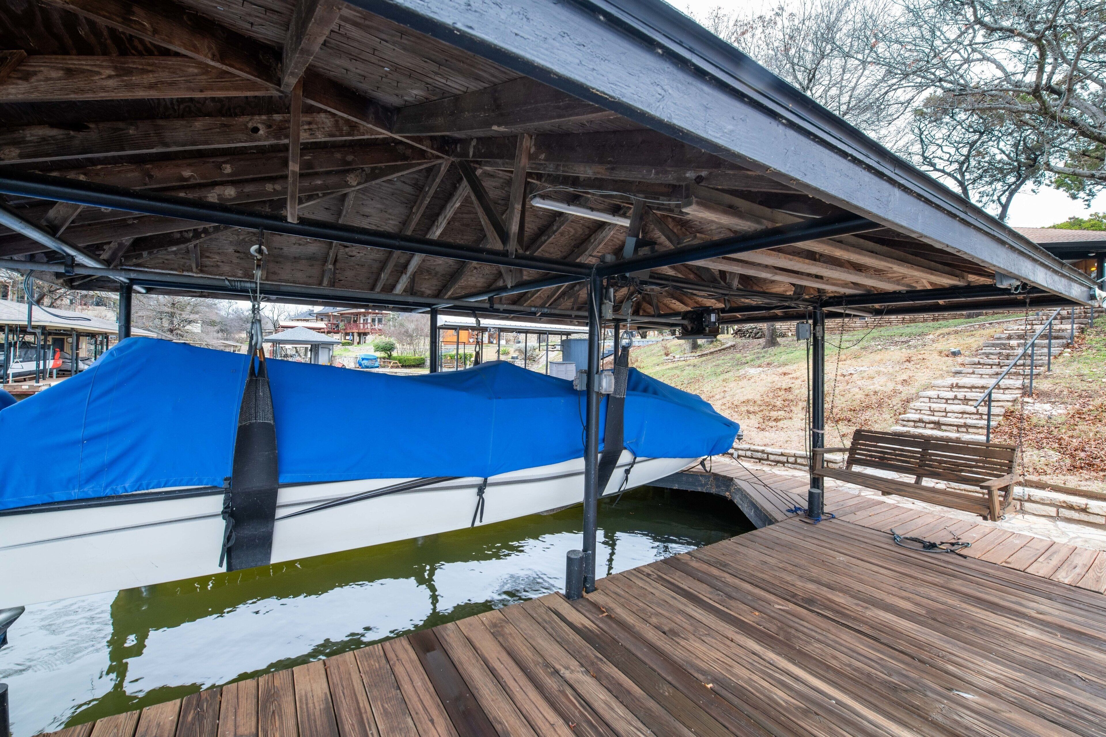 A covered boat dock with a wooden deck and a bench.