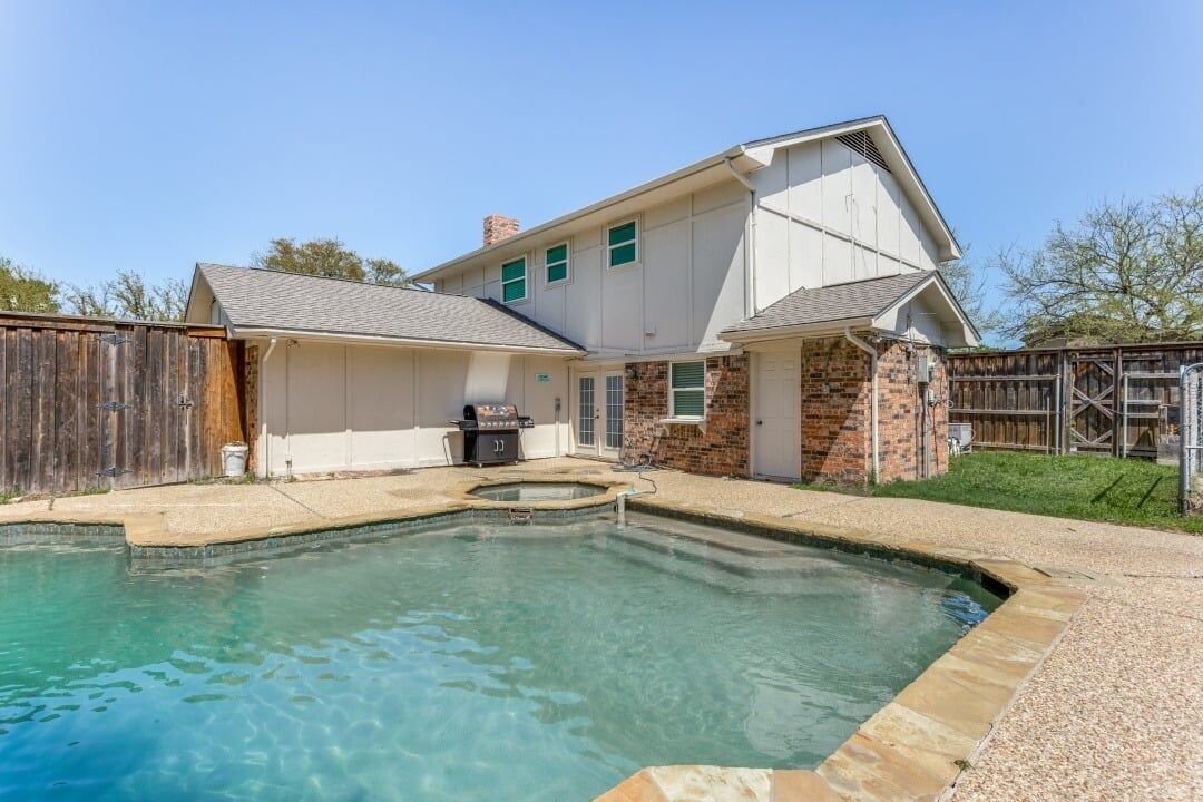 A residential property with a swimming pool, a covered patio, and a brick exterior.
