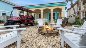A patio area with a fire pit, white Adirondack chairs, and a red golf cart. - Serenity Now-Free Golf Cart-Hot Tub-Comm Pool (Destin)