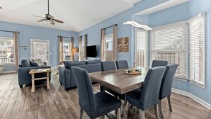 A spacious living room with a sofa, a dining table, and a ceiling fan. - Serenity Now-Free Golf Cart-Hot Tub-Comm Pool (Destin)