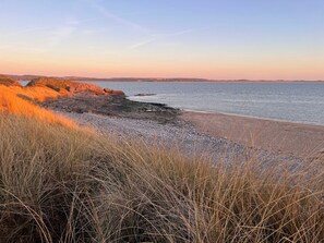 A beach with rocky terrain and dry grass in the foreground. - Natterjack Cottage - Access to the Western Lakes (Millom)