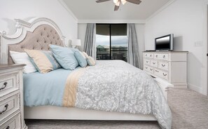 A bedroom with a large bed, a dresser, a television, and a ceiling fan. - Phoenix On The Bay 1513 3 Bedroom Condo (Orange Beach)