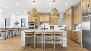 Une cuisine moderne dotée d’un îlot central, de meubles en bois et de luminaires suspendus.