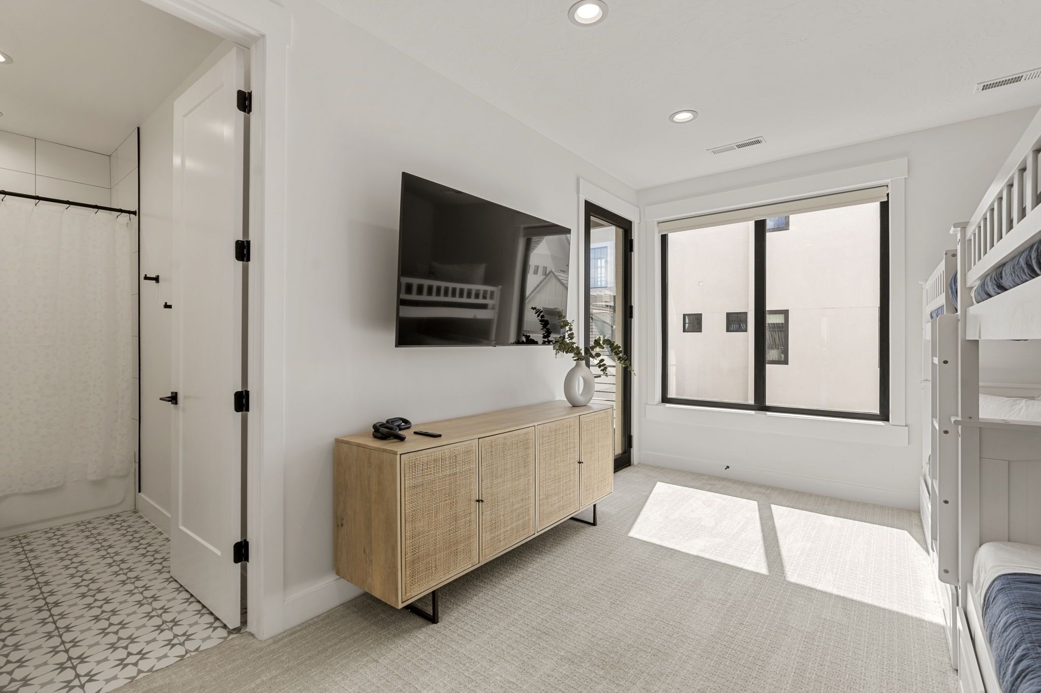 Une chambre à coucher moderne avec un lit superposé, une grande fenêtre, un téléviseur à écran plat et une armoire en bois.
