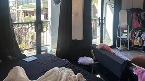 A bedroom with a bed, a bench, and a balcony with curtains.