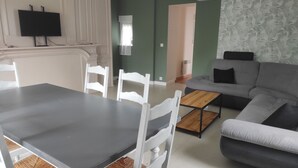 A living room with a grey sofa, a wooden coffee table, and white chairs. - Welcome to la casa T4 RDC *** (Giffaumont-Champaubert)