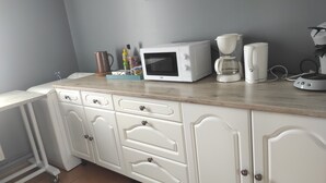 A kitchen with white cabinets, a microwave, a coffee maker, and a kettle on the countertop. - Welcome to la casa T4 RDC *** (Giffaumont-Champaubert)