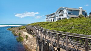 Ein Küsteneigentum mit einer Holzpromenade, die zu einem großen, mehrstöckigen Gebäude mit Balkonen führt.