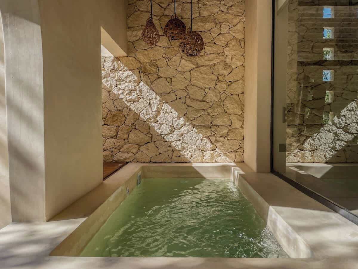 A spa area with a stone wall, a hot tub, and hanging wicker lamps.