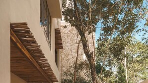 A courtyard with a stone wall, a wooden deck, and a pool. - Boutique La Veleta Condo with Private Pool Terrace (Tulum)
