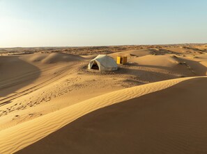 Paisaje desértico con dunas de arena y una estructura parecida a una tienda.