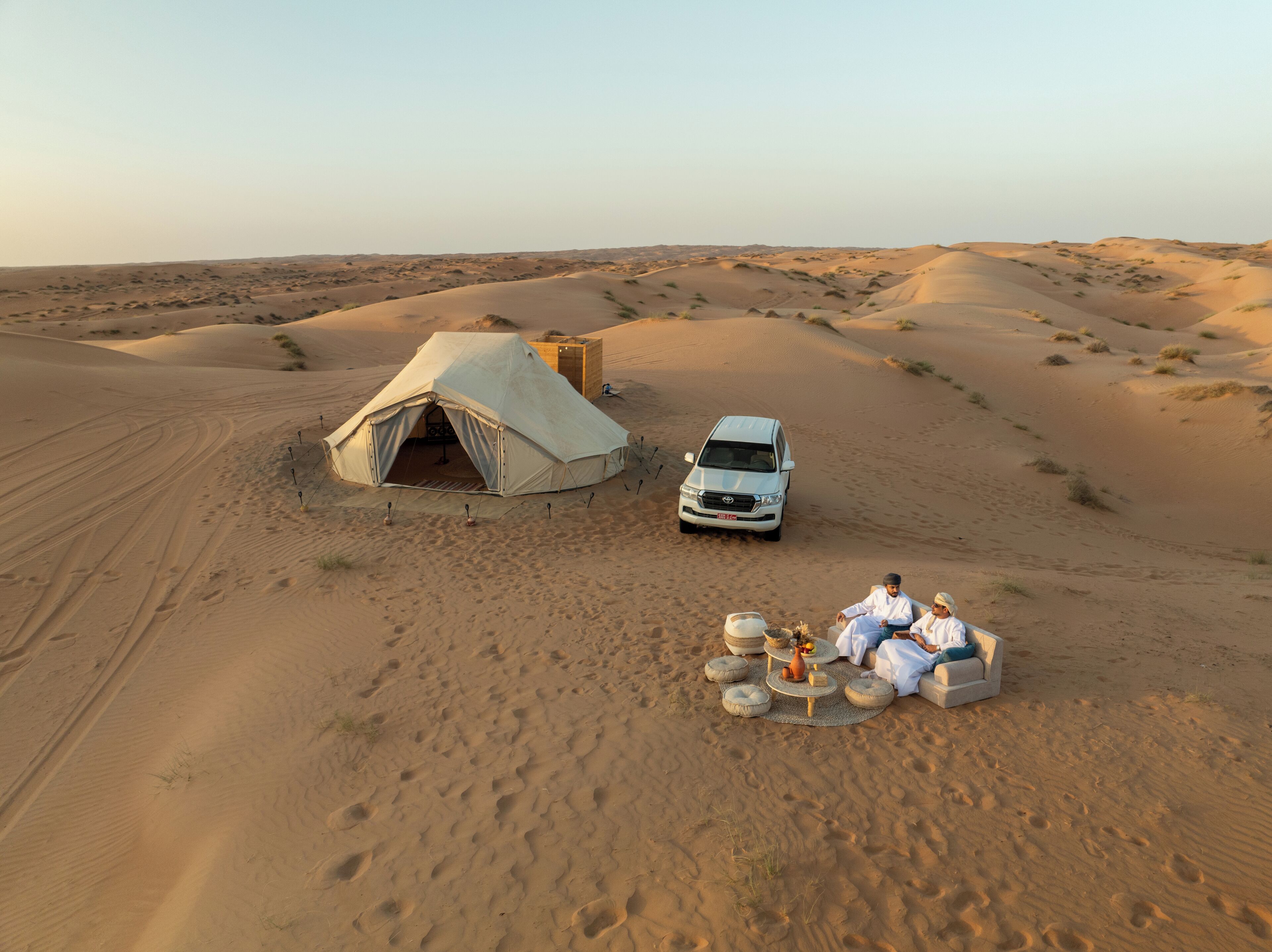 Un campament al desert amb una tenda i un vehicle.
