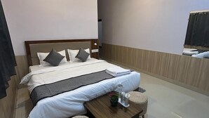 Una moderna camera d'hotel con un letto grande, una ventola a soffitto, un comodino con una pianta e un piccolo sgabello.