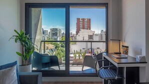 Un espacio de oficina moderno con un amplio ventanal, un escritorio, una silla y una planta en maceta.