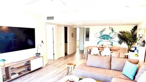 A living room with a flat-screen TV, a sofa, a coffee table, and a dining area with a table and chairs.