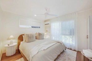Bedroom with curved timber bedhead and soft neutral linen - Urban Getaway Bargara Central (Bargara)